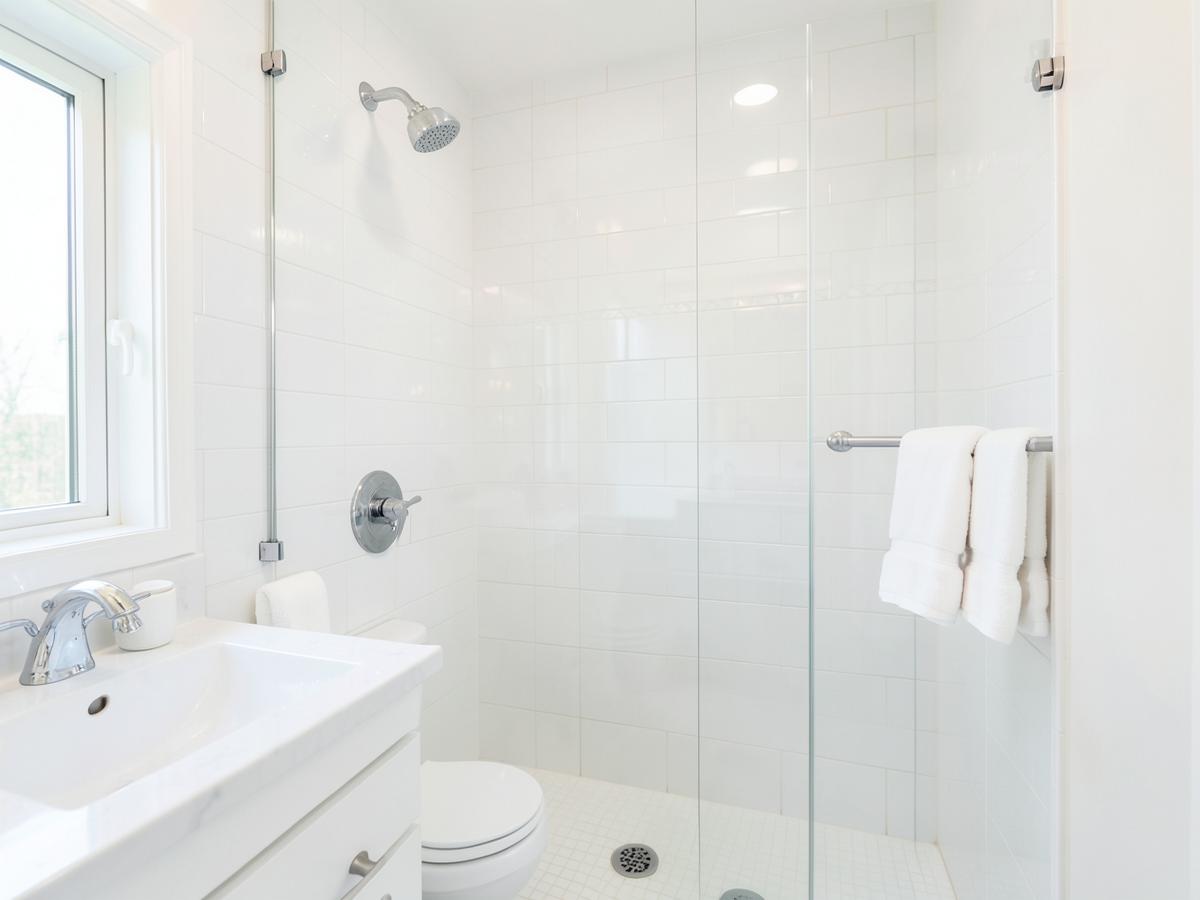 Bright white tiled bathroom with streak-free glass shower after a bathroom deep clean in Fort Worth, TX